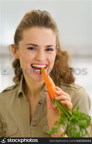 Young housewife eating fresh carrot