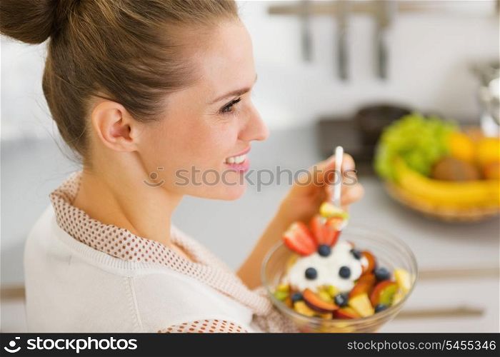 Young housewife eating fruits salad . rear view