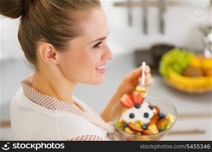 Young housewife eating fruits salad . rear view