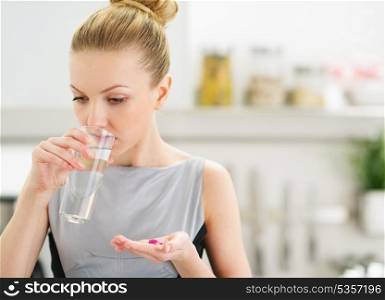 Young housewife eating pills and drinking water