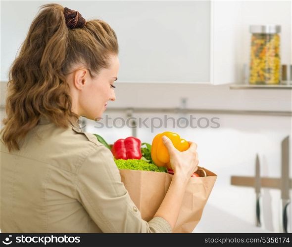 Young housewife examines purchases after shopping in kitchen. rear view