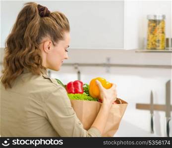 Young housewife examines purchases after shopping in kitchen. rear view