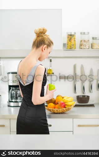 Young housewife forming plate of fruits . rear view