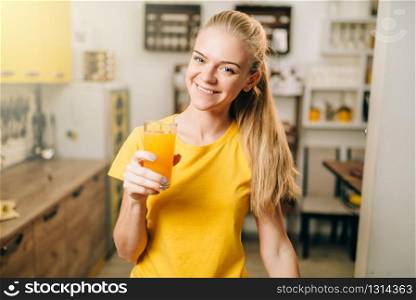 Young housewife with glass of orange juice on the kitchen, bio food. Vegetarian diet, healthy lifestyle concept