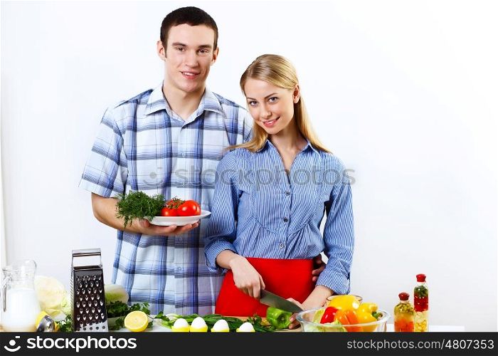Young husband and wife together coooking at home