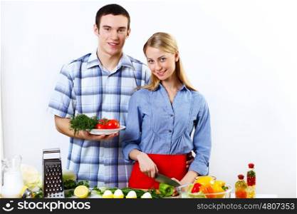 Young husband and wife together coooking at home
