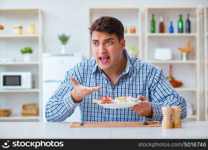 Young husband eating tasteless food at home for lunch