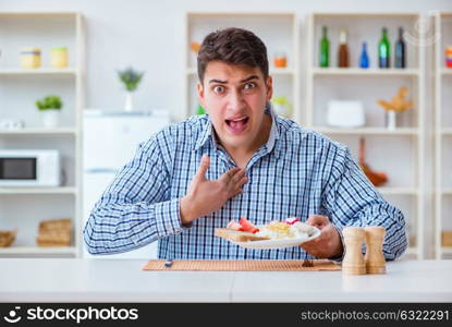 Young husband eating tasteless food at home for lunch