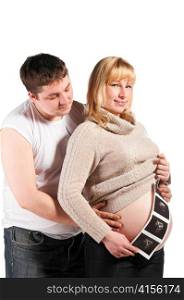 young husband is standing and hugging his pregnant wife with ultrasonic scan