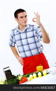 Young husband wearing apron at home cooking meal
