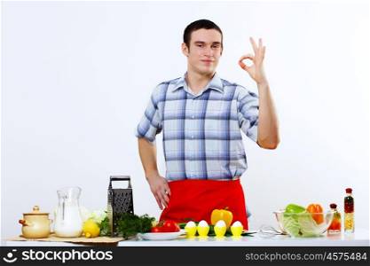 Young husband wearing apron at home cooking meal