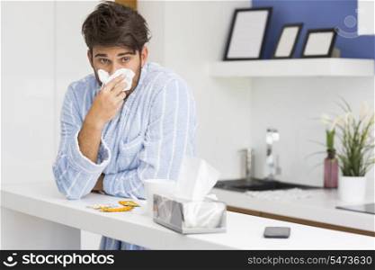 Young ill man blowing nose in tissue paper