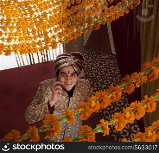 Young Indian bridegroom talking on mobile phone while looking up