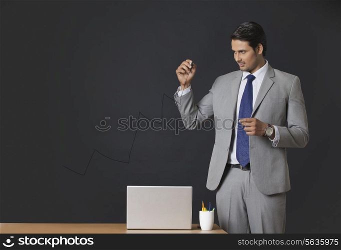 Young Indian businessman drawing graph on transparent screen at office