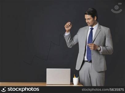 Young Indian businessman drawing graph on transparent screen at office