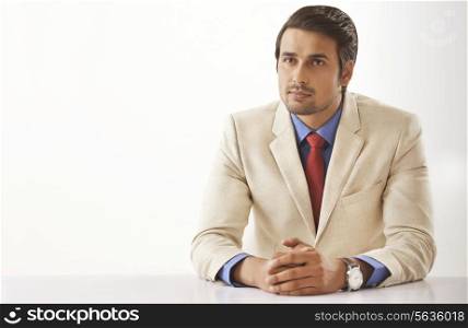 Young Indian businessman looking away while sitting at office desk