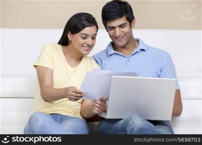 Young Indian couple reading document while using laptop