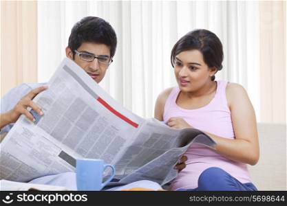 Young Indian couple reading newspaper together