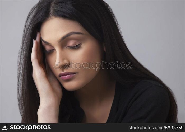Young Indian female suffering from headache over colored background