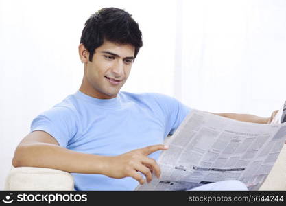 Young Indian man reading newspaper