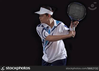 Young Indian woman playing tennis over black background