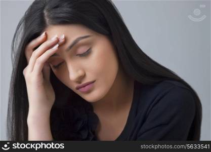 Young Indian woman suffering from headache isolated over colored background