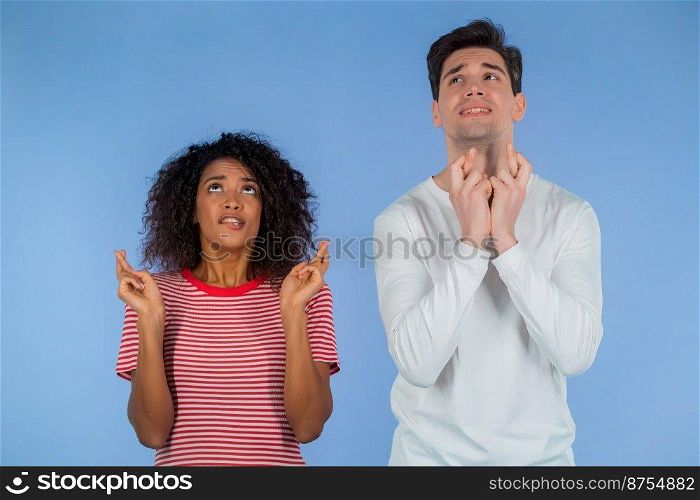 Young interracial couple praying over blue background. White man and african woman begging someone satisfy desires, help with. High quality. Young interracial couple praying over blue background. White man and african woman begging someone satisfy desires, help with.