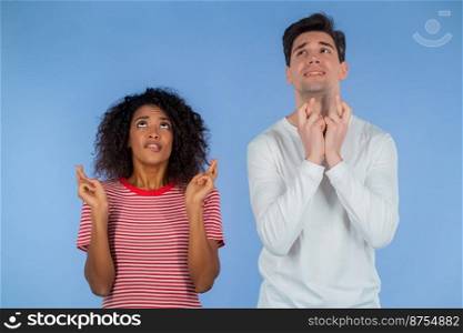 Young interracial couple praying over blue background. White man and african woman begging someone satisfy desires, help with. High quality. Young interracial couple praying over blue background. White man and african woman begging someone satisfy desires, help with.