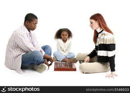 Young interracial family, parents playing chess while child looks on