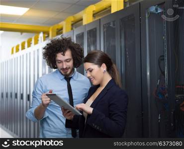 Young IT engineer showing working data center server room to female chief engineer who holding tablet computer