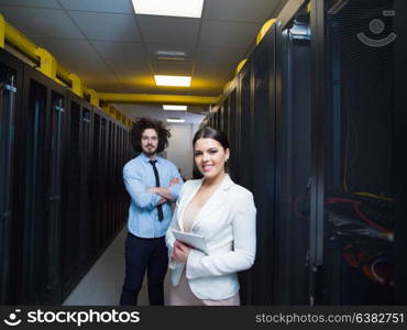 Young IT engineer showing working data center server room to female chief engineer who holding tablet computer