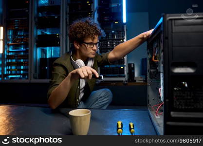 Young IT technician using flashlight to find problem with computer in modern data center. Teenager networking engineer at work. Young IT technician using flashlight to find problem with computer in modern data center