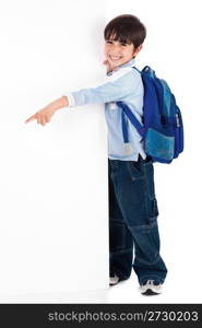 Young kid happily standing behind the board and pointing to empty space on white isolated background