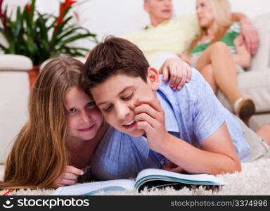 Young kids studying close to the camera with family in the background