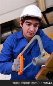 Young laborer using saw