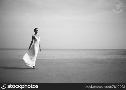 Young lady in white dress jumping on the beach