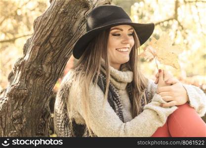 Young lady with leaf outdoor. Seasonal specific. Gorgeous lovely young girl holding gold brown leaf. Beauty trendy woman spending time in autumnal park.