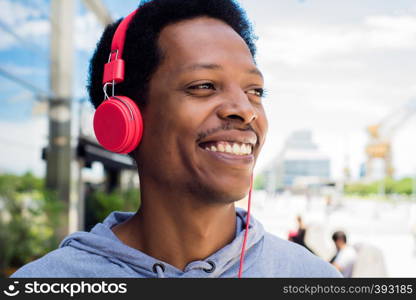 Young latin man listening music with headphones in the city. Enjoying concept.