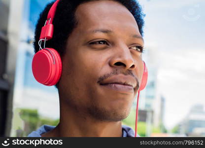 Young latin man listening music with headphones in the city. Enjoying concept.