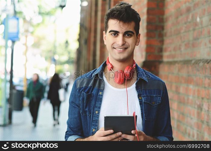 Young latin man touching at tablet at the street. Urban concept.