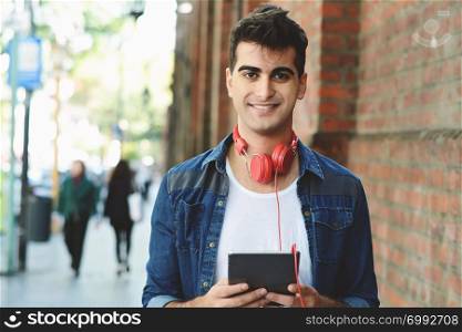 Young latin man touching at tablet at the street. Urban concept.