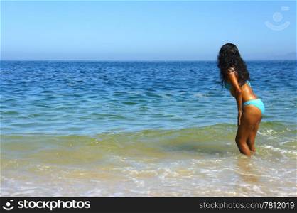 Young latin woman going into the ocean.