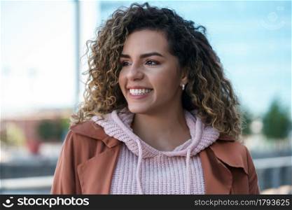 Young latin woman smiling while standing outdoors on the street. Urban concept.