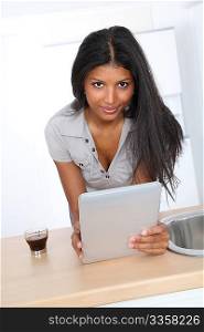 Young latin woman using electronic tablet in home kitchen