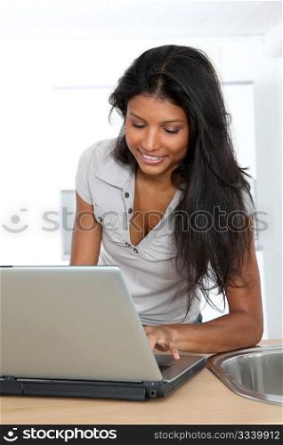 Young latin woman using laptop computer in home kitchen