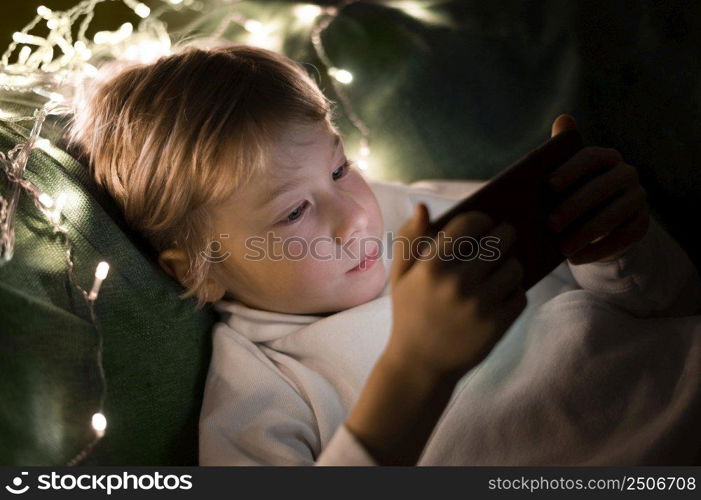 young little boy using smartphone bed night