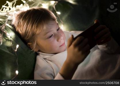 young little boy using smartphone bed night