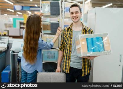 Young love couple choosing core of mattress in furniture store showroom. Man and woman looking samples for bedroom in shop, husband and wife buys goods for modern home interior. Couple choosing core of mattress, furniture store