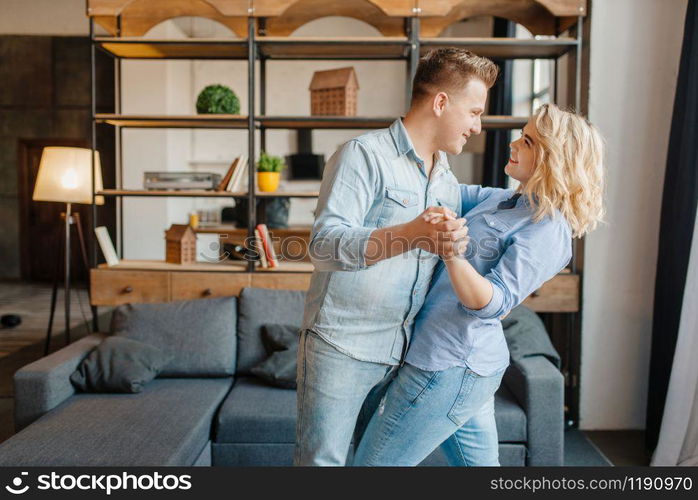 Young love couple dancing at home, romantic dinner. Man and woman relaxing in living room. Happy lifestyle, beautiful relationship