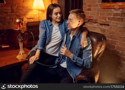 Young love couple relax in hookah bar, hooka chill out. Shisha smoking, traditional bong culture, tobacco aroma for relaxation, rest with hooka. Young couple relax in hookah bar, hooka chill out